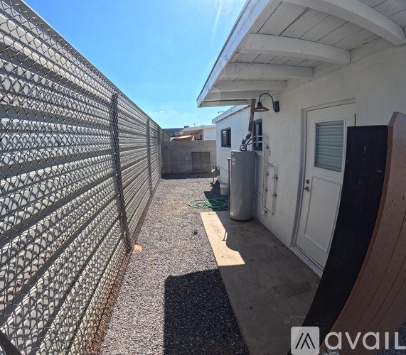 A narrow alley with a metal fence on the left and a white door on the right.