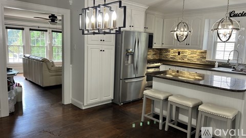 A kitchen with white cabinets and a stainless steel refrigerator.