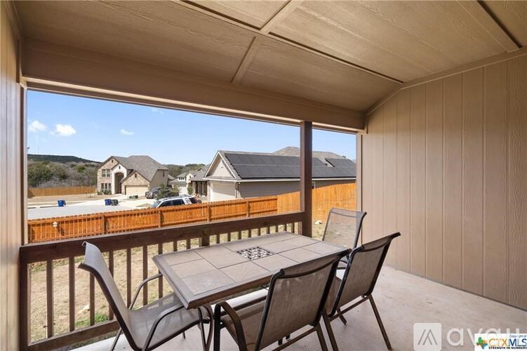 A patio with a table and chairs overlooking a residential area.