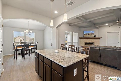 A kitchen with a granite countertop and a dining table with chairs.