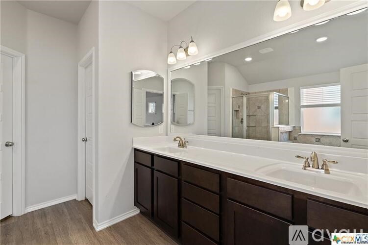 A bathroom with a white sink and brown cabinets.