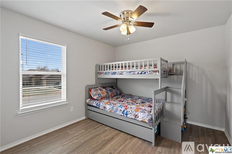 A room with a bunk bed and a ceiling fan.