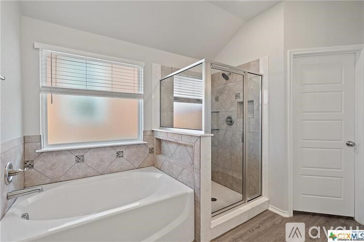 A bathroom with a white tub and a walk-in shower.