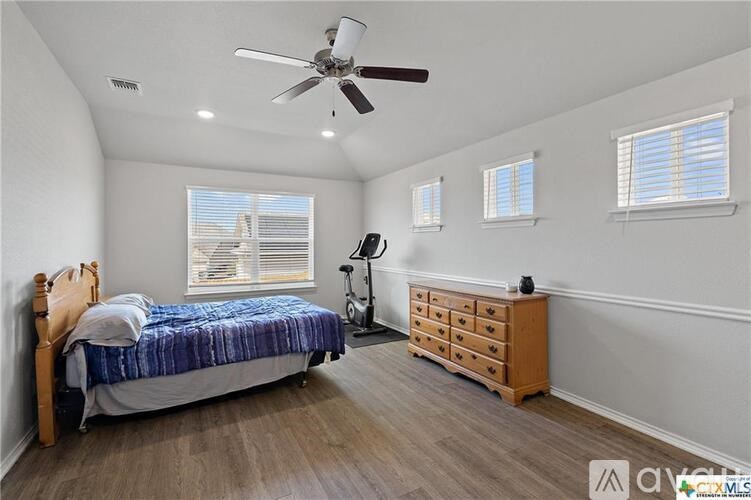 A bedroom with a bed, dresser, and window.