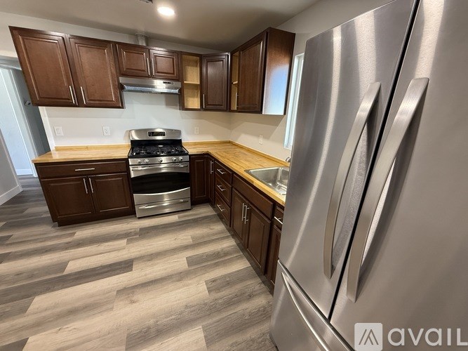 A kitchen with a stainless steel refrigerator and wooden cabinets.