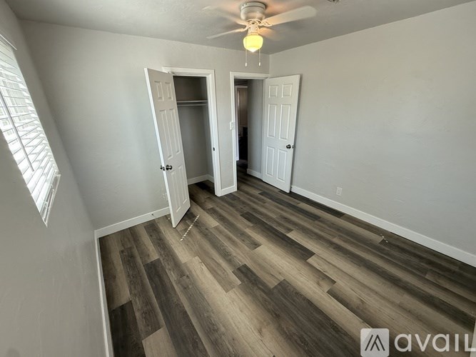 A room with a ceiling fan and wooden flooring.