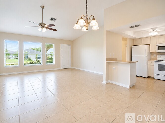 A large, empty room with a kitchenette and a chandelier.