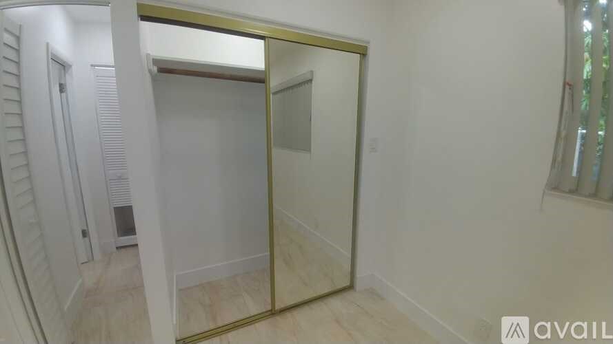 A room with a mirrored door and a white wall.