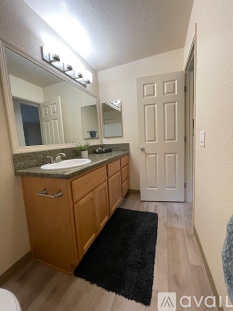 A bathroom with a sink, mirror, and wooden cabinets.