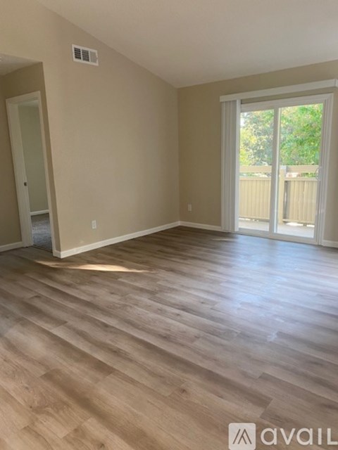 A room with wooden flooring and a sliding glass door leading outside.