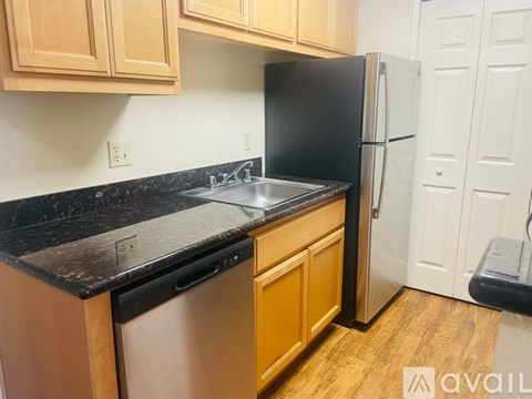 A kitchen with a black fridge and wooden cabinets.