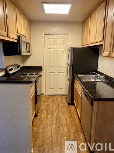 A kitchen with wooden cabinets and a black refrigerator.