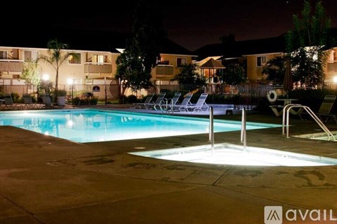 A swimming pool at night with lights on.