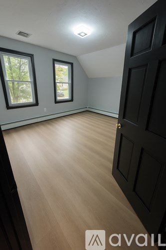 A room with a black door and two windows.