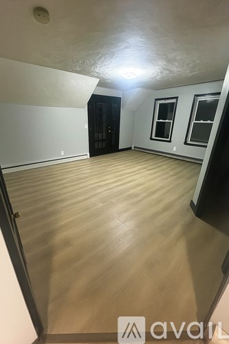 A room with wooden flooring and white walls.