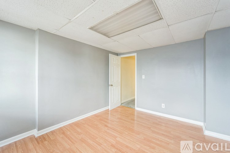 A room with wooden flooring and a door leading to another room.