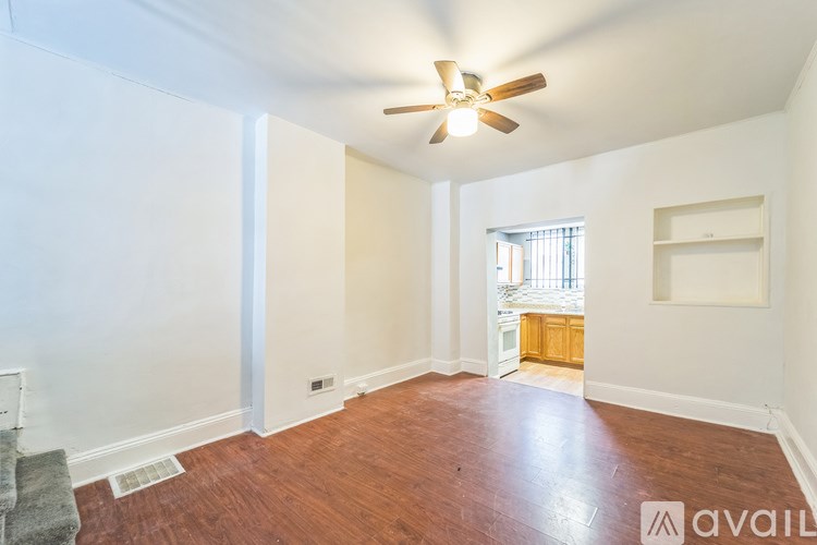 A room with a ceiling fan and wooden flooring.