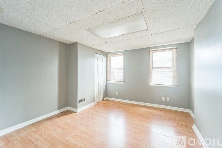A room with wooden flooring and two windows.