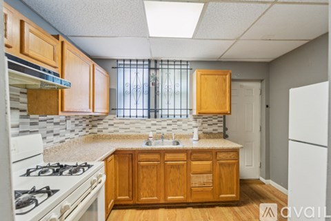 A kitchen with wooden cabinets and a white stove top oven.