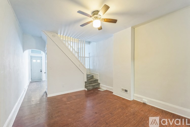 A room with a wooden floor and a staircase leading to the second floor.