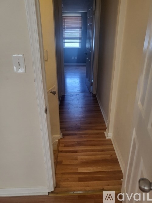A hallway with wooden floors and a white door.