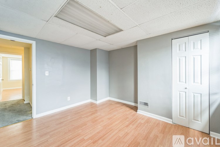 A room with wooden floors and white walls, with a door on the right side.