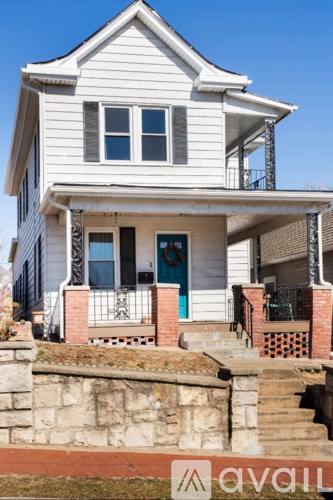 A white house with a blue door and a brick staircase.
