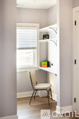 A white chair is in front of a white shelf with a few items on it.