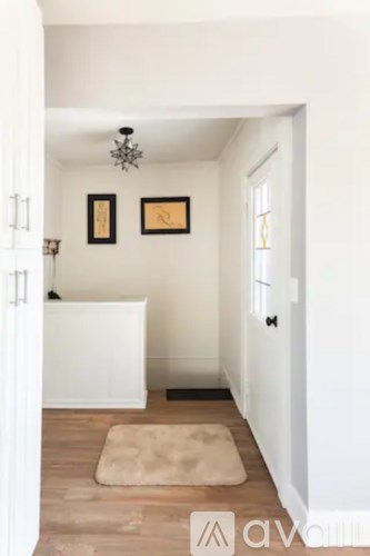 A hallway with a rug on the floor and two pictures on the wall.