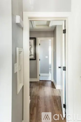 A hallway with a wooden floor and white walls.