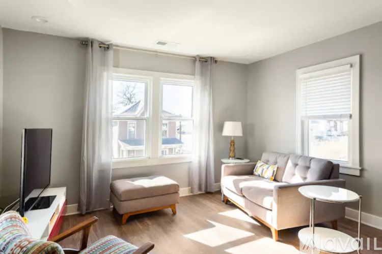 A living room with a grey couch, a white table, and a television.
