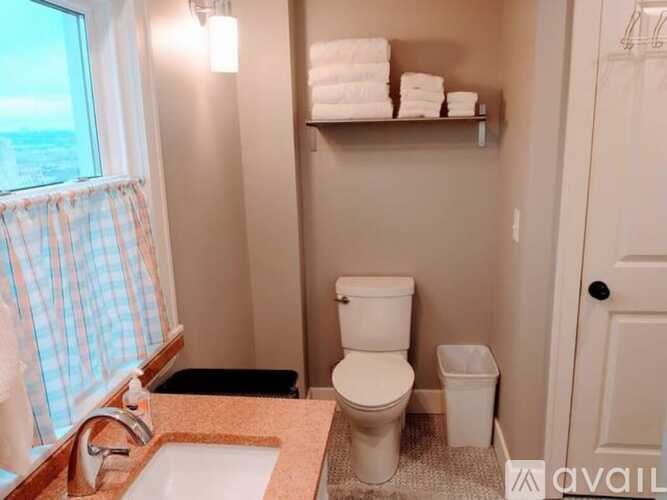 A small bathroom with a toilet, sink, and a window.