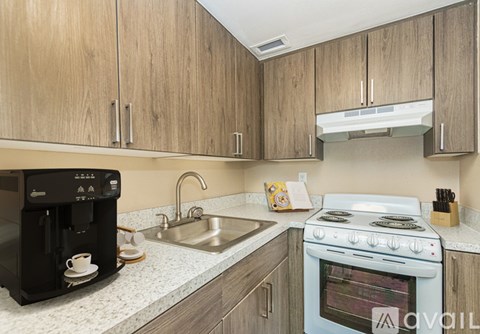 A kitchen with a white stove top oven and a black coffee maker.