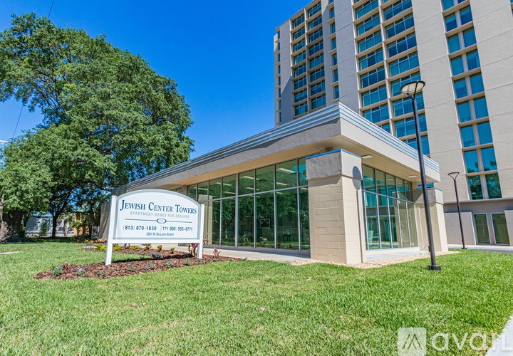 A sign for the Jewish Center Towers is in front of a modern building.