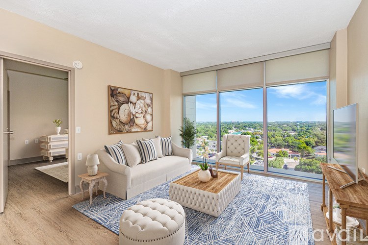 A living room with a couch, ottoman, and a view of the city.