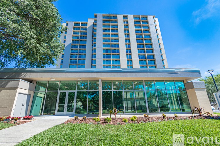 A modern building with a glass facade and a landscaped front yard.
