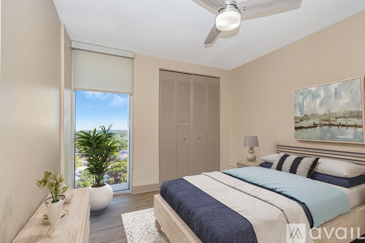 A bedroom with a bed, a ceiling fan, and a painting on the wall.