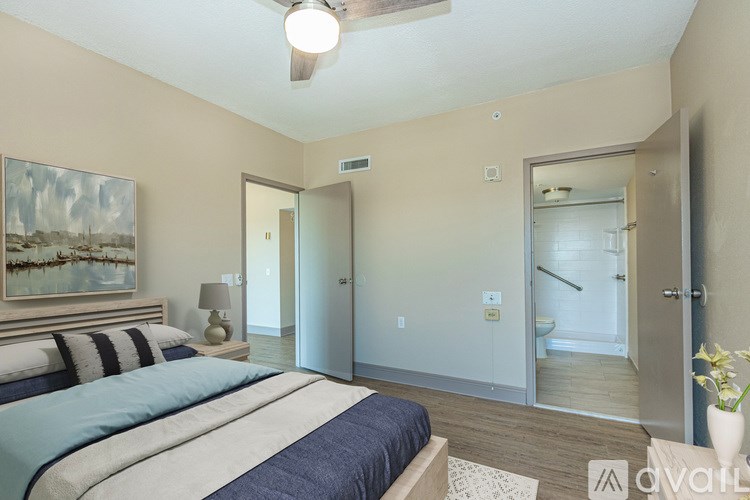 A bedroom with a bed, a painting, a lamp, and a mirror.