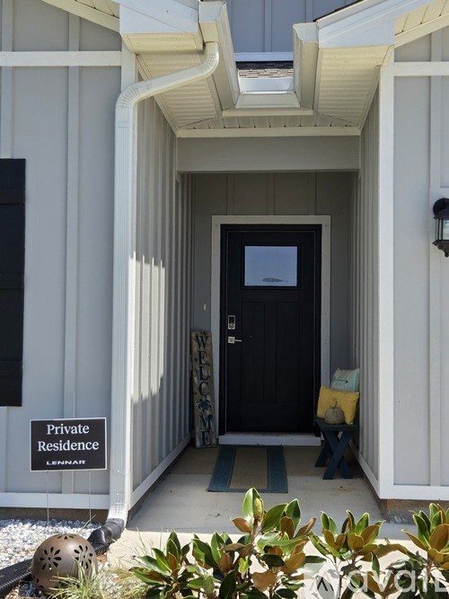 A black door is in a white building with a sign that says Private Residence.