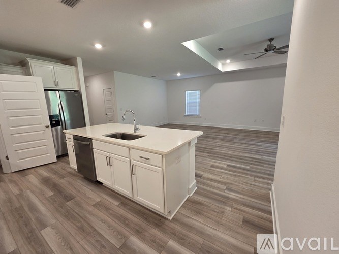 A kitchen with white cabinets and a wooden floor.