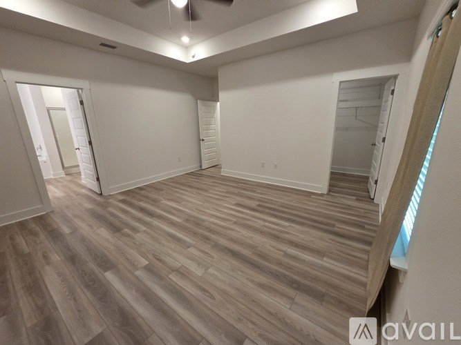 A spacious room with wooden flooring and white walls.