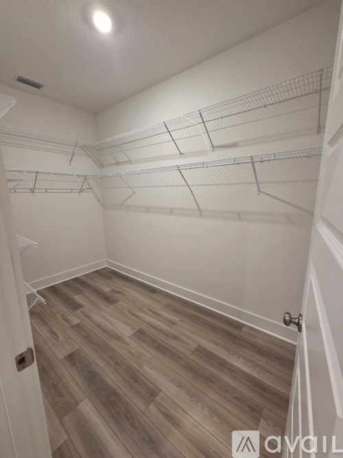 A walk-in closet with white shelving and wood flooring.