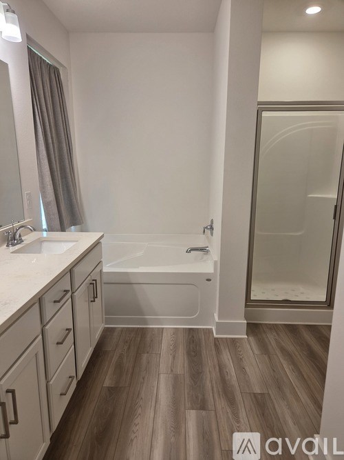 A bathroom with a tub, sink, and wooden floors.