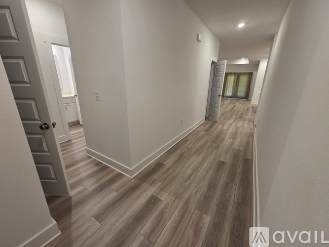 A hallway with wood flooring and white walls.