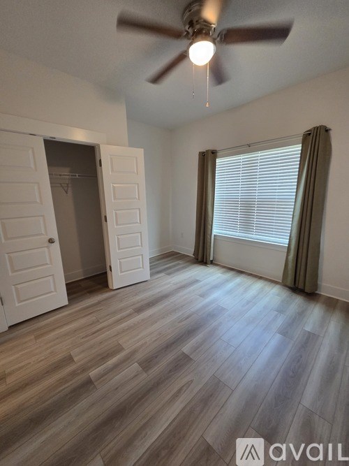 A room with a ceiling fan and a door leading to another room.