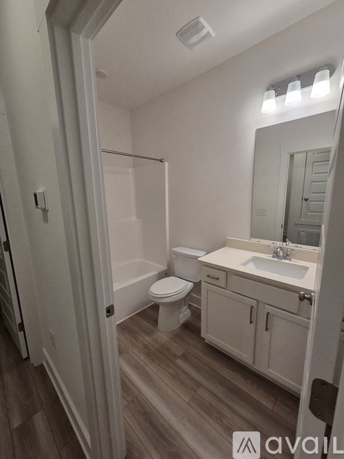 A bathroom with a toilet, sink, and mirror.