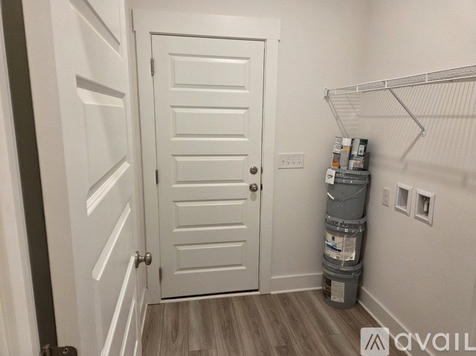 A white door is in a room with a shelf and a stack of containers.