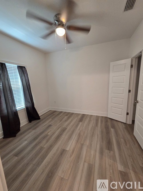 A room with a ceiling fan and wooden flooring.