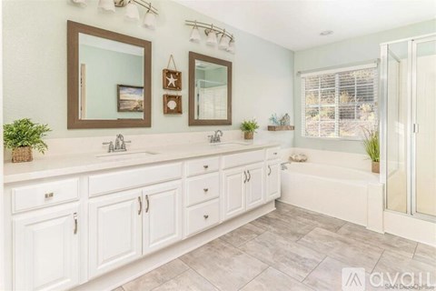 A bathroom with white cabinets and a large mirror above the sink.