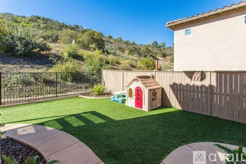 A backyard with a dog house and a fence.